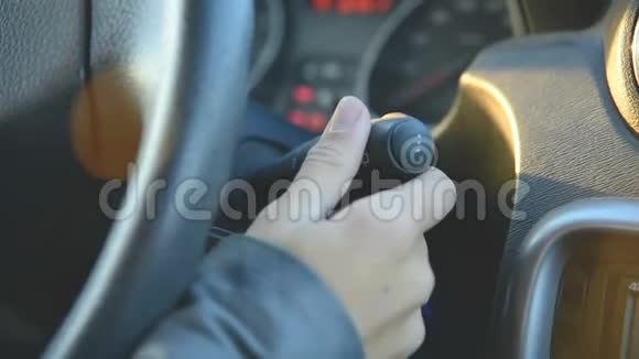一个女孩的特写镜头打开方向盘上的雨刷开车的女人女孩开关上的手视频的预览图