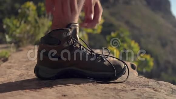 在悬崖上系鞋带的徒步旅行者视频的预览图
