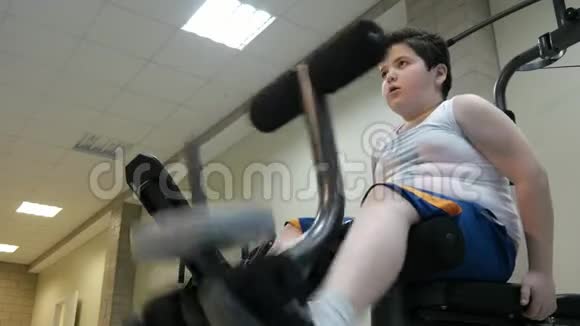 在体育馆用运动训练器材训练男孩大肚子减肥的概念视频的预览图