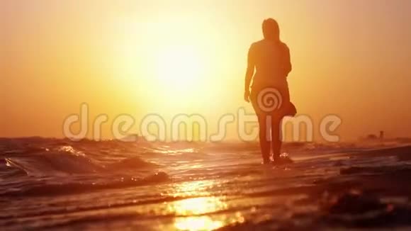 女人在日落时光着脚在海滩上慢动作鸟儿在海面上飞翔1920x1080视频的预览图