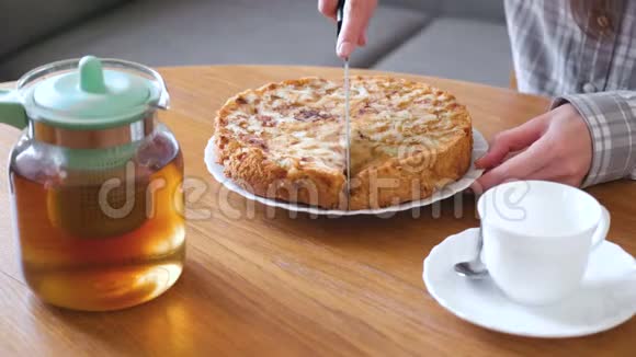 特写女人手切自制的苹果派茶和茶壶在桌子上视频的预览图