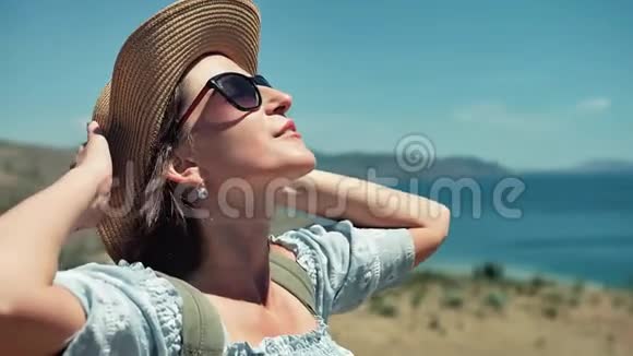 侧视放松的欧洲女性日光浴用手和手臂触摸帽子视频的预览图