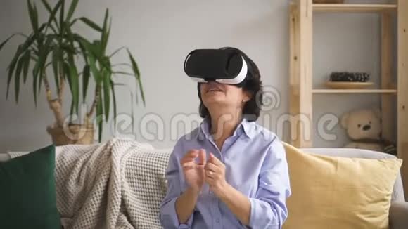 坐在沙发上戴着虚拟现实眼镜的女人视频的预览图