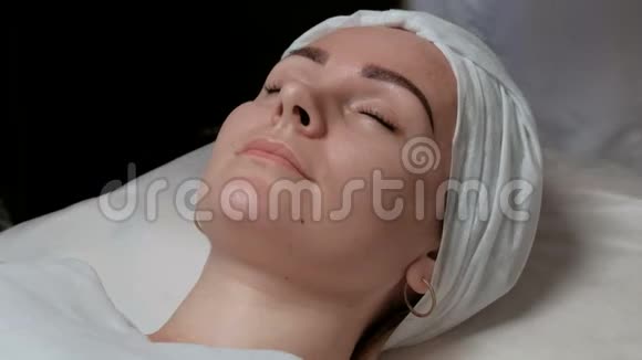 盒疗法一位美丽的欧洲女孩在美容院做面部护理的肖像女性的双手视频的预览图