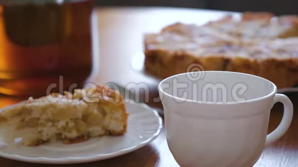 特写的女人她的手从茶壶里倒了一杯茶碟子上自制的苹果派切片视频的预览图