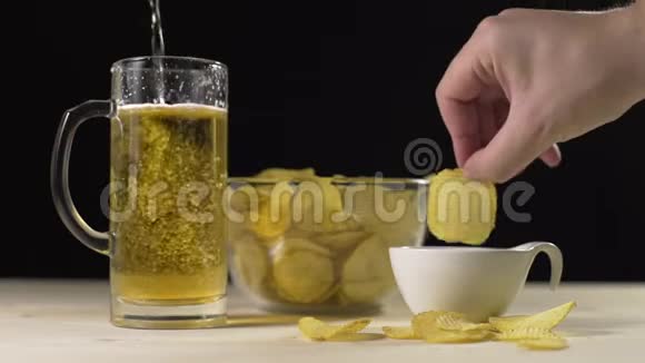 黄金啤酒慢慢地倒入玻璃杯中人们拿着薯片蘸着酱汁小吃啤酒啤酒视频的预览图