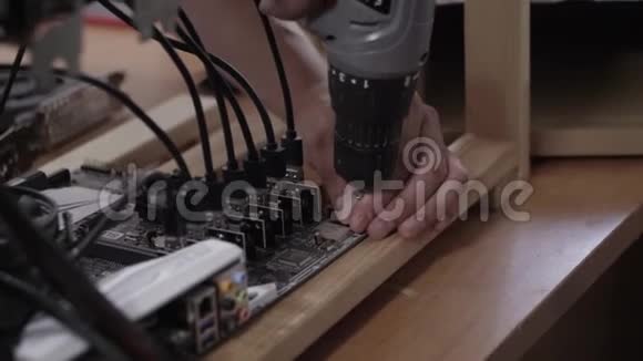 男人手用电子螺丝刀把主板和木板连接起来视频的预览图