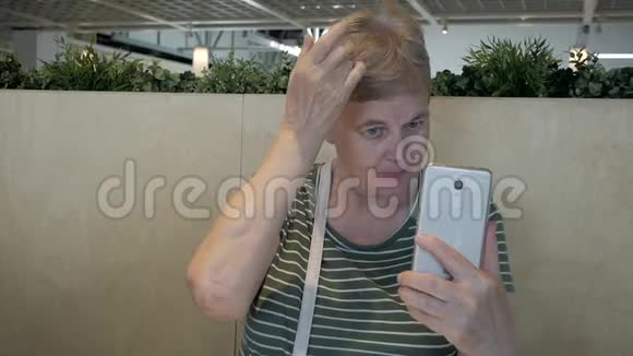 一位年长的女士在智能手机上照镜子修头发视频的预览图
