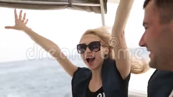 年轻女子坐快艇头发随风飘动成年夫妇在游艇甲板上享受暑假欧洲视频的预览图