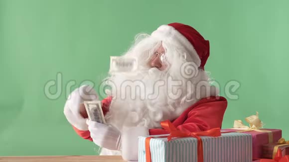 满足的圣诞老人把钞票从一捆钱扔在桌子上钱在桌子上色彩在后台视频的预览图