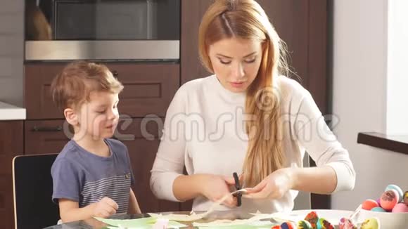 妈妈和儿子画鸡蛋一家人坐在厨房里准备复活节视频的预览图