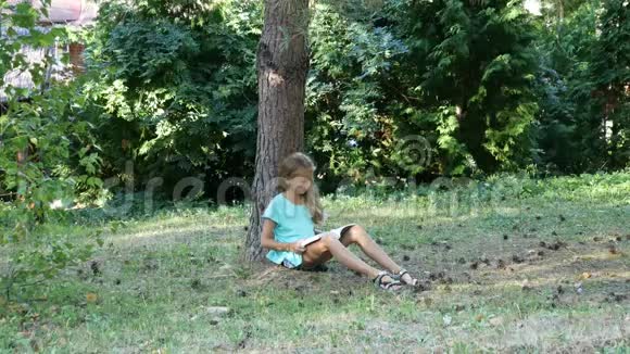 孤独的女孩坐在阳光明媚的草坪上在树影里看书视频的预览图