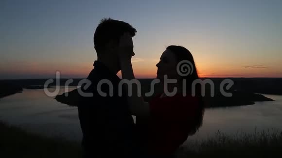 摄影师拍摄情侣相爱在河边接吻日落的光视频的预览图