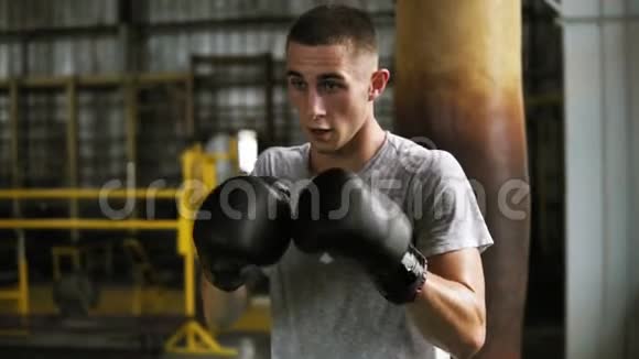 积极愤怒的男性拳击手在健身房的训练过程一个男人用拳击袋打拳练习踢腿的肖像视频的预览图