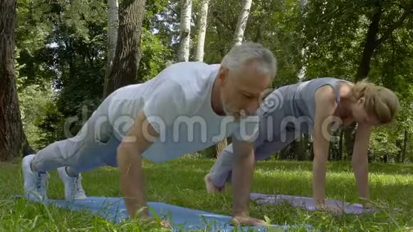 活跃的老年人在公园做俯卧撑和瑜伽慢动作视频的预览图