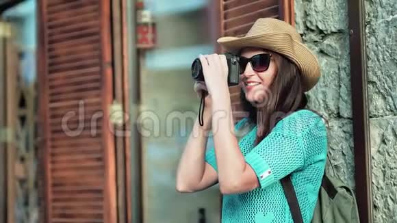 年轻的女旅游摄影师戴太阳镜戴帽子用专业相机拍照视频的预览图