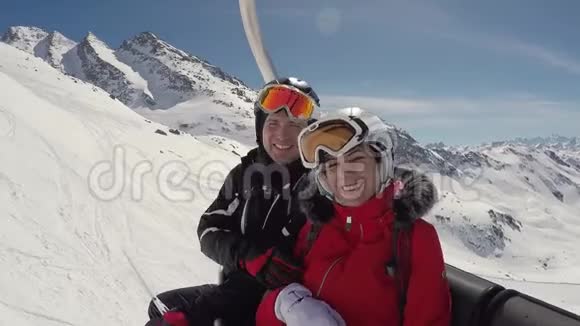 两个滑稽的滑雪者在冬天的山上坐在滑雪电梯上视频的预览图