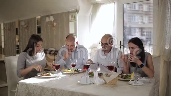 四个朋友在餐厅吃肉喝红酒在杯子里视频的预览图