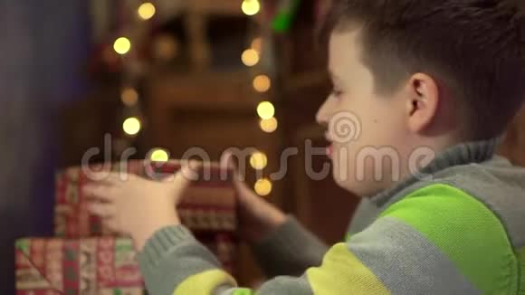 男孩少年摇着支票准备圣诞礼物堆放在树下的礼物视频的预览图
