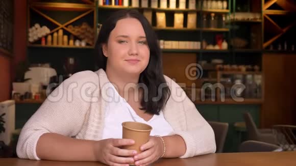 看着摄像机微笑着捧着一大杯咖啡的富西白种人女孩视频的预览图