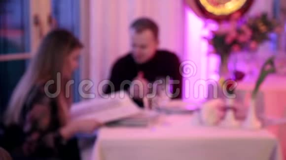 背景模糊两个相爱的人坐在餐桌旁的餐馆里视频的预览图