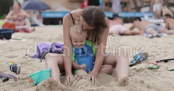 一位年轻的母亲正在海边的沙滩上和一个小孩玩耍视频的预览图