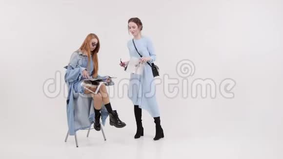 两个女人在白色工作室看风格杂志微笑视频的预览图