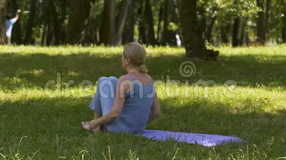 健康的生活方式老太太在公园的垫子上做瑜伽体式业余锻炼视频的预览图