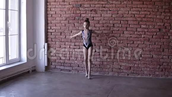 可爱的女孩在窗户附近穿着艺术紧身衣从事艺术体操年轻体操运动员在体操中跳跃视频的预览图
