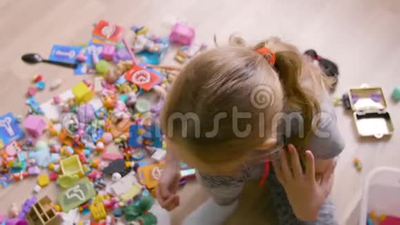 在家里地板上玩玩具的金发女孩的俯视图视频的预览图