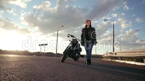 一个穿着皮夹克和手套的老妇人骑自行车站在摩托车附近看上去笔直有空的视频的预览图