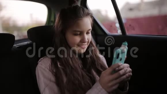 少女和妈妈一起坐在车里使用智能手机视频的预览图