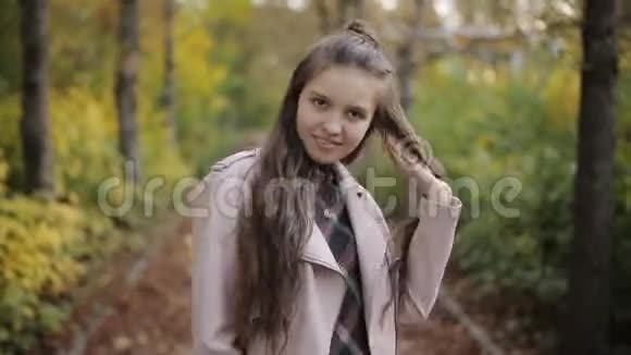 少女在秋天公园玩她的头发看相机视频的预览图