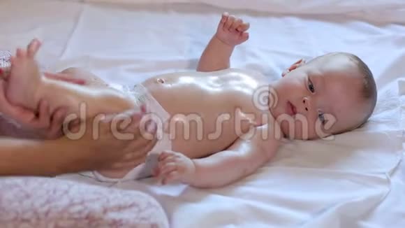 妈妈做新生儿宝宝按摩在身体上涂油在白底视频的预览图