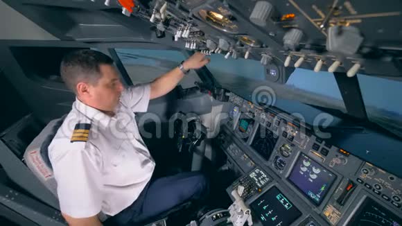 男飞行员正在调整他的椅子并在起飞时按下按钮视频的预览图