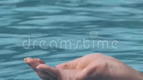 在阳光明媚的日子里雌性手玩水的特写镜头用手指抓住它倒进游泳池人类视频的预览图