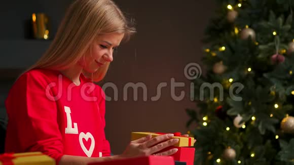 带着圣诞帽的女孩许愿并打开圣诞礼物包节日和新年的概念视频的预览图