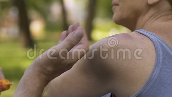 男人用防晒霜使女性的肩膀皱缩防止晒伤慢动作视频的预览图
