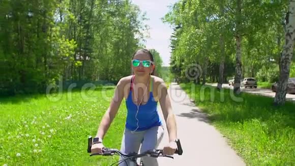 女人骑着一辆带智能手表心率监视器的自行车智能手表的概念戴眼镜的快乐年轻女子视频的预览图