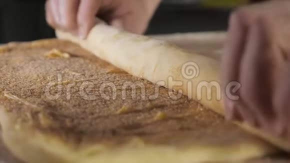面包师用肉桂糖和黄油将面团卷成一卷在桌子上视频的预览图