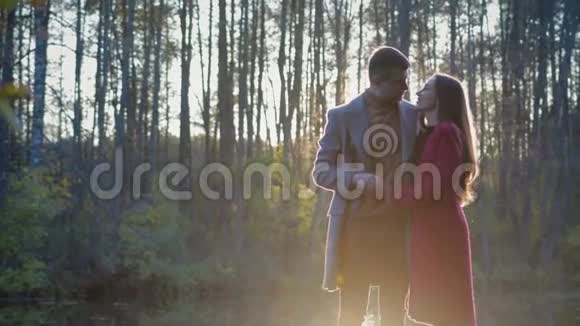 一对浪漫的情侣站在湖边亲吻他们之间有阳光和阳光视频的预览图