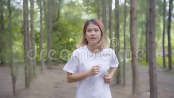 慢动作健康美丽年轻运动运动亚洲跑步妇女穿运动服装在森林小径上跑步和慢跑视频的预览图