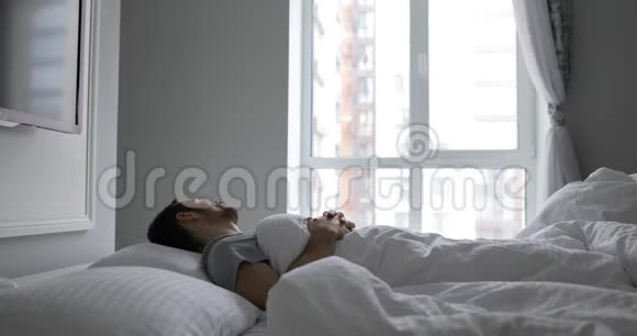 清晨醒来的男人躺在床上伸着胳膊视频的预览图