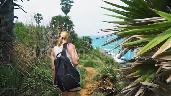 旅游女孩正沿着热带雨林的小径散步有棕榈树的海滨视频的预览图