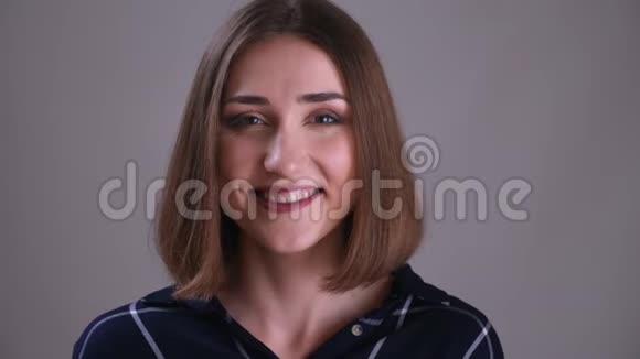 年轻漂亮的短头发女性面部特写镜头带着微笑的面部表情看镜头视频的预览图