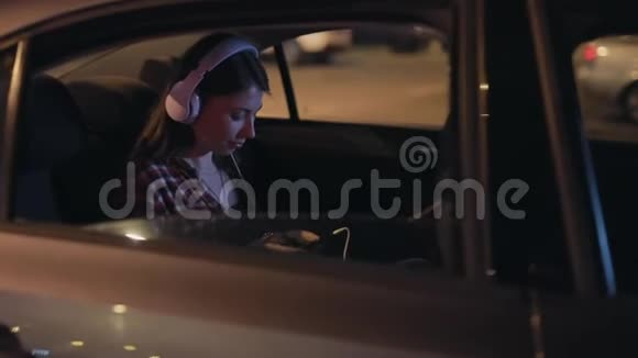 女乘客在车里用立体声耳机听音乐视频的预览图