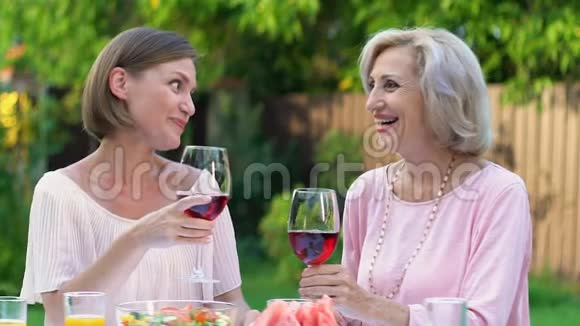 女儿和岳母在户外愉快地用一杯酒交流视频的预览图