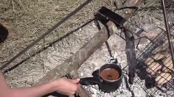 女人在营地的篝火上煮咖啡和早餐视频的预览图