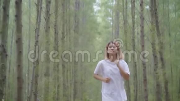 慢动作健康美丽年轻运动运动亚洲跑步妇女穿运动服装在森林小径上跑步和慢跑视频的预览图