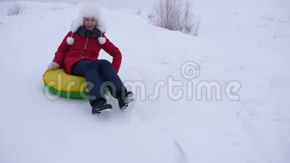 快乐的孩子滑在雪上滑在雪橇上油管上女孩在公园里冬天玩白色的快乐少女视频的预览图